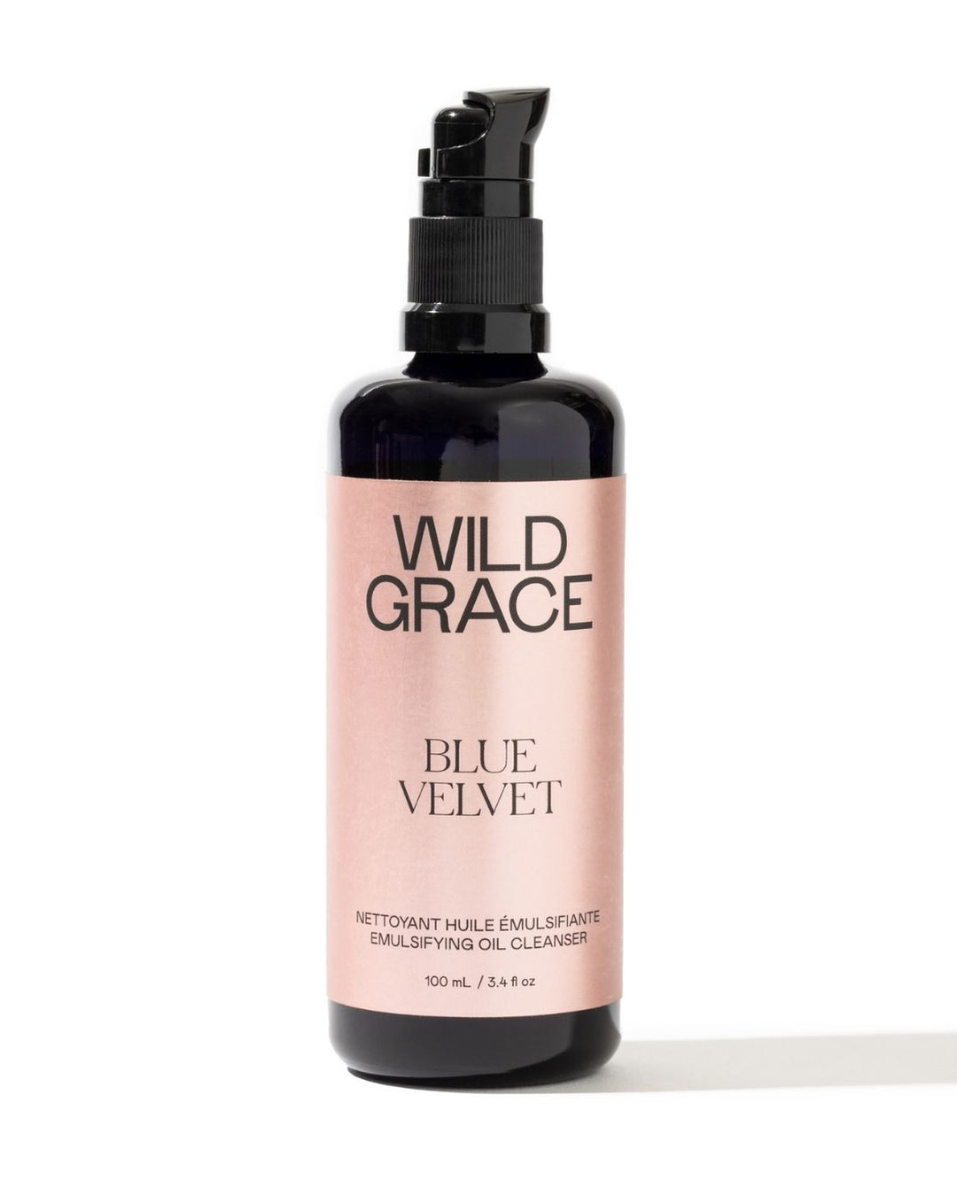 A 100 mL pump bottle of Wild Grace Blue Velvet Emulsifying Oil Cleanser, featuring a black bottle and a metallic pink label, set against a plain white background.