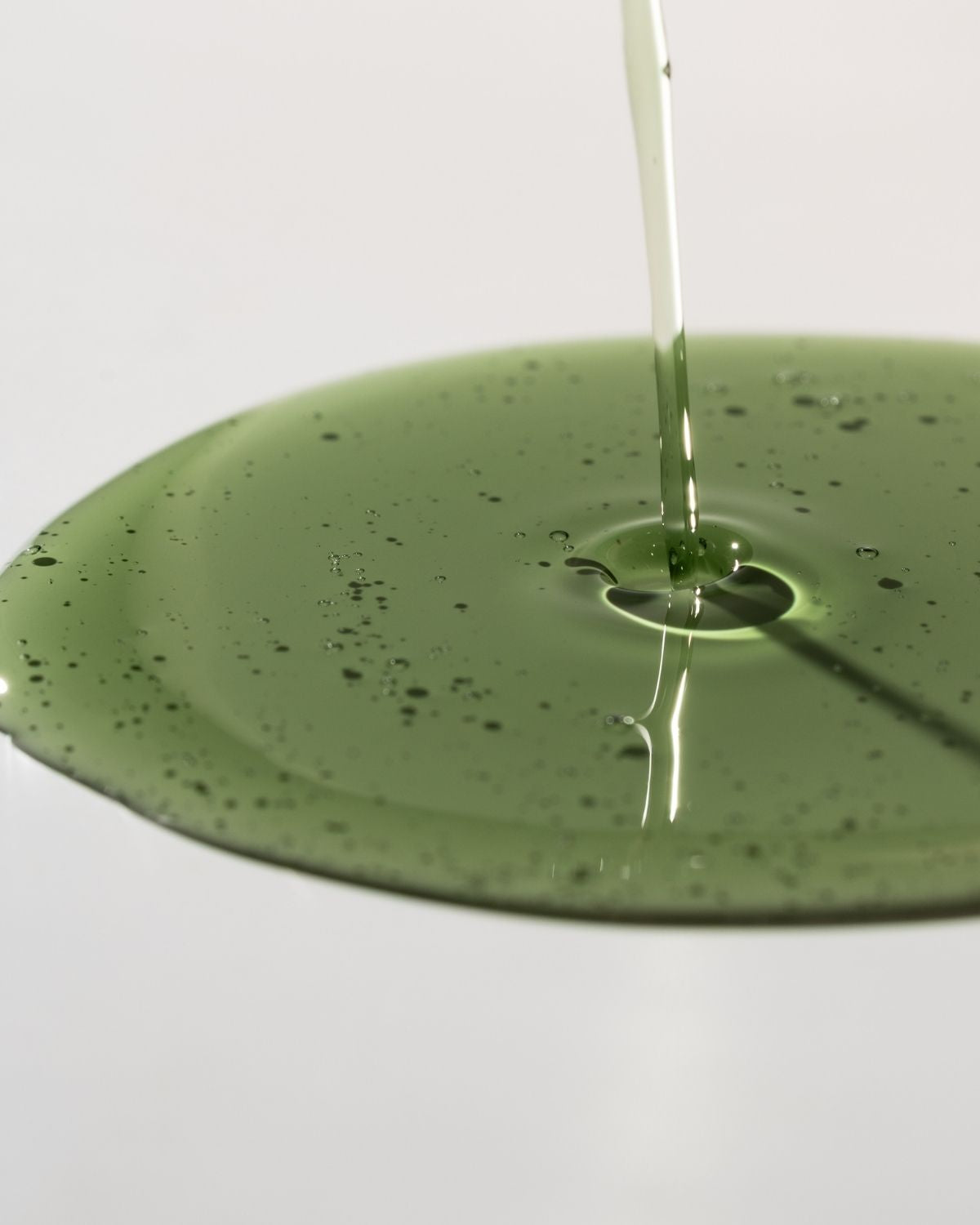 Green liquid being poured onto a green surface with a white background