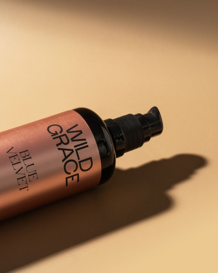 Wild Grace Blue Velvet lip gloss bottle on a beige background