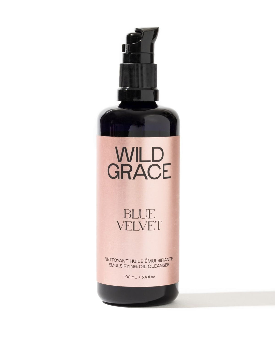 A 100 mL pump bottle of Wild Grace Blue Velvet Emulsifying Oil Cleanser, featuring a black bottle and a metallic pink label, set against a plain white background.