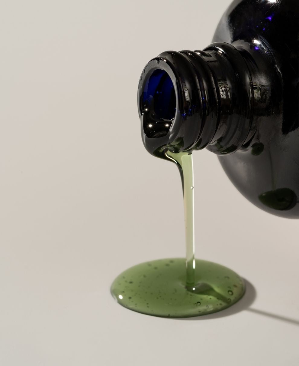 Blue bottle pouring green liquid onto a white surface