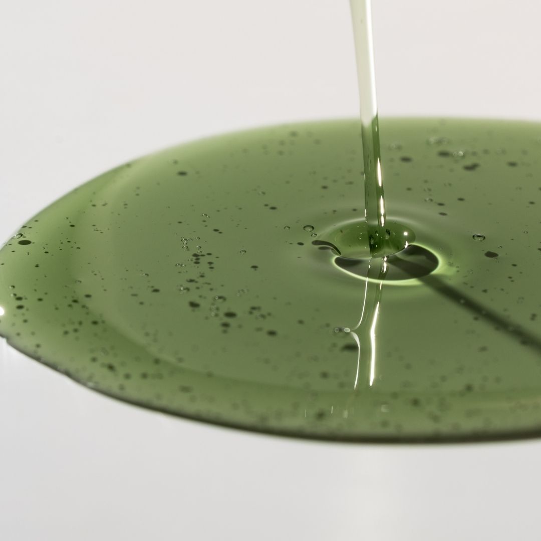 Green liquid being poured onto a green surface with a white background