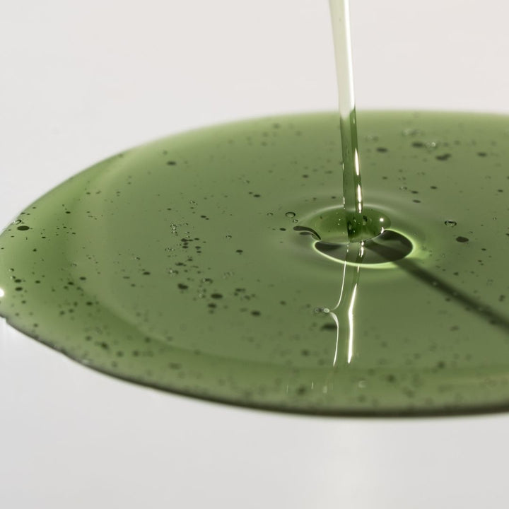 Green liquid being poured onto a green surface with a white background