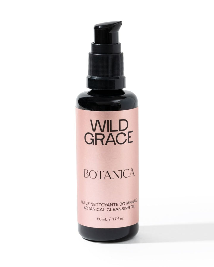 A bottle of Wild Grace Botanica Botanical Cleansing Oil on a white background. The product is in a black bottle with a black pump dispenser and a light pink label featuring black text.