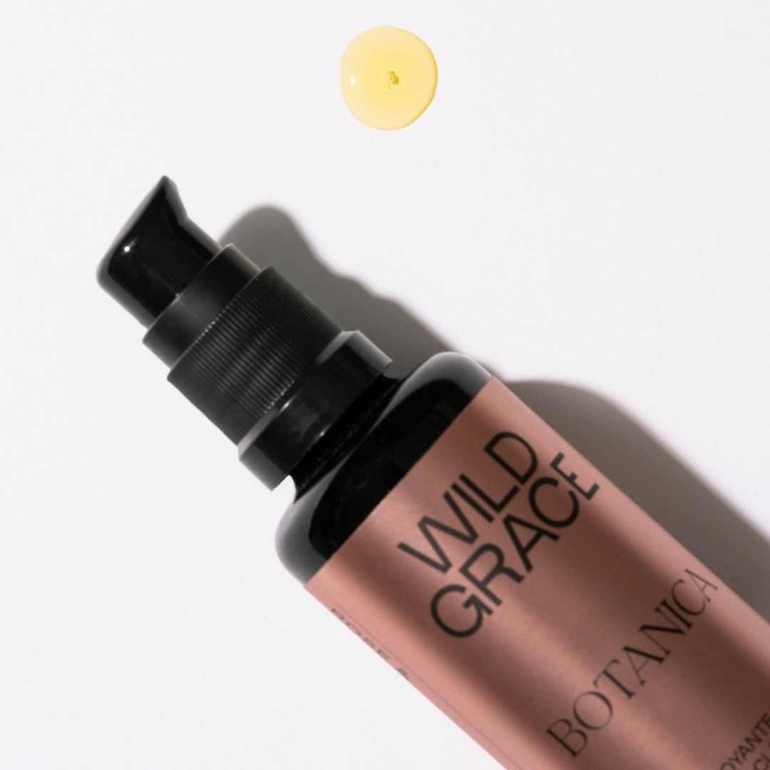 Wild Grace Botanica makeup bottle with a droplet of product on a white background