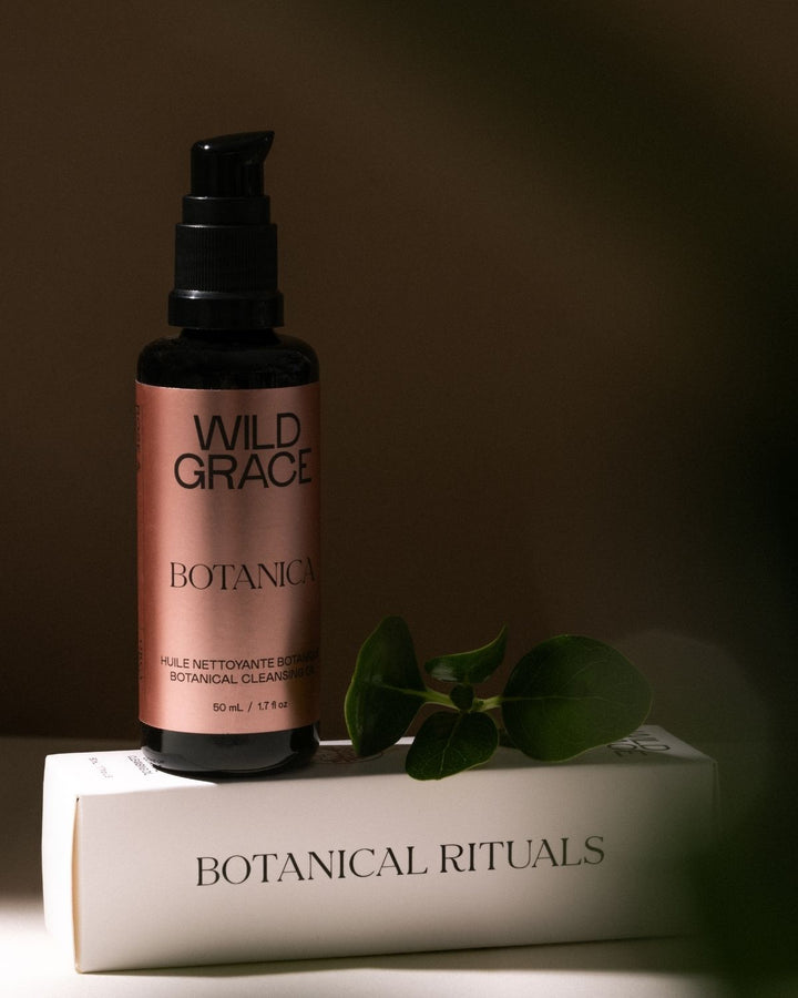 Bottle of Wild Grace Botanica product on a box with a leaf, against a dark background