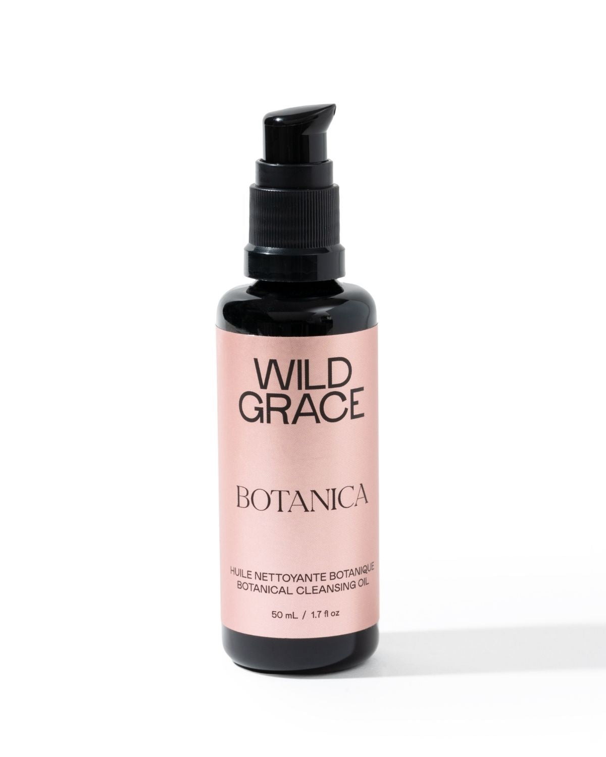A bottle of Wild Grace Botanica Botanical Cleansing Oil on a white background. The product is in a black bottle with a black pump dispenser and a light pink label featuring black text.