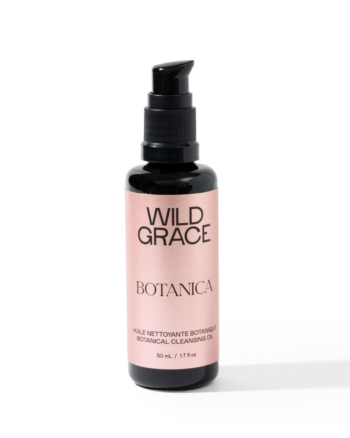 A bottle of Wild Grace Botanica Botanical Cleansing Oil on a white background. The product is in a black bottle with a black pump dispenser and a light pink label featuring black text.