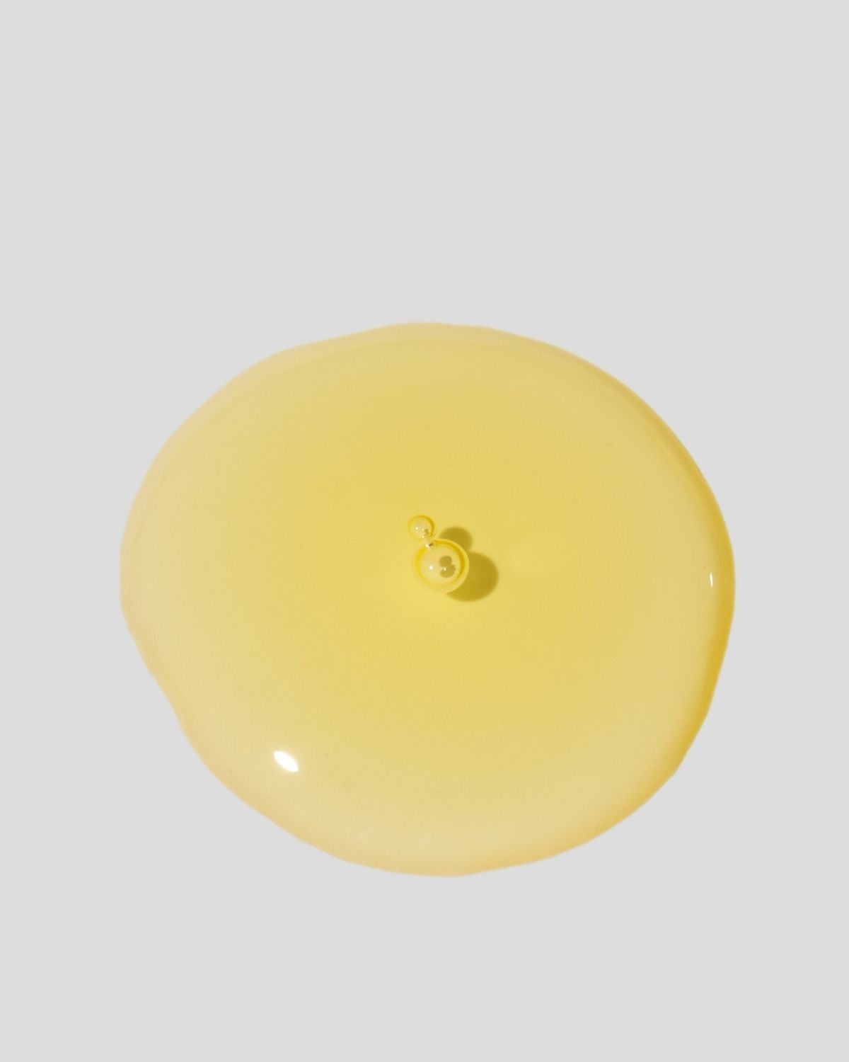 Yellow oil texture of Botanica cleansing oil on gray background