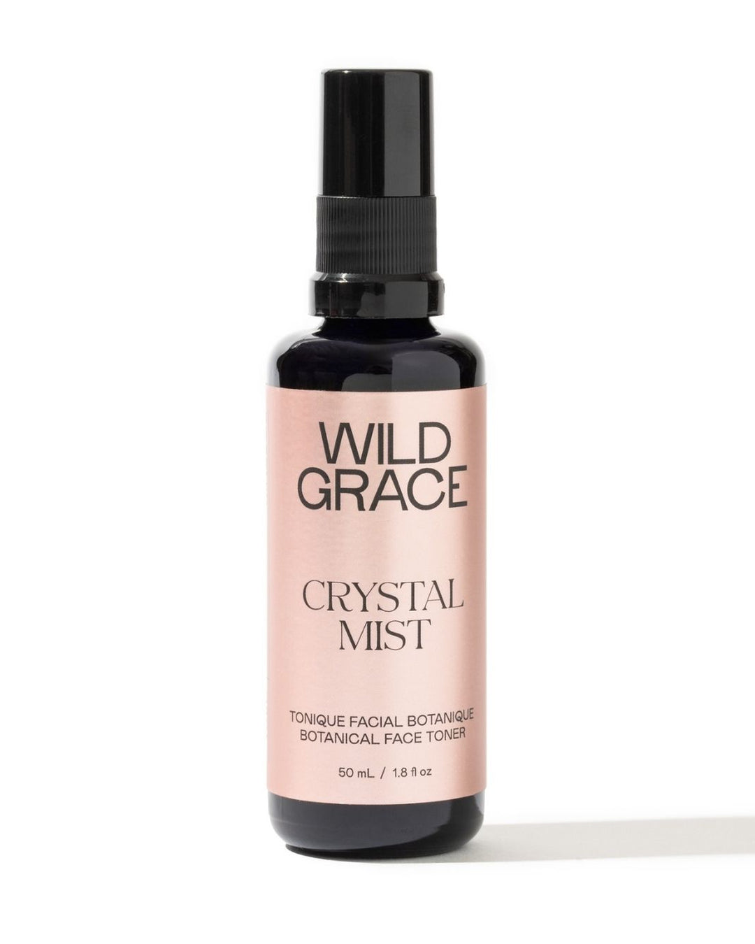 A bottle of Wild Grace Crystal Mist facial toner with a black spray top and a pale pink label, set against a plain white background.