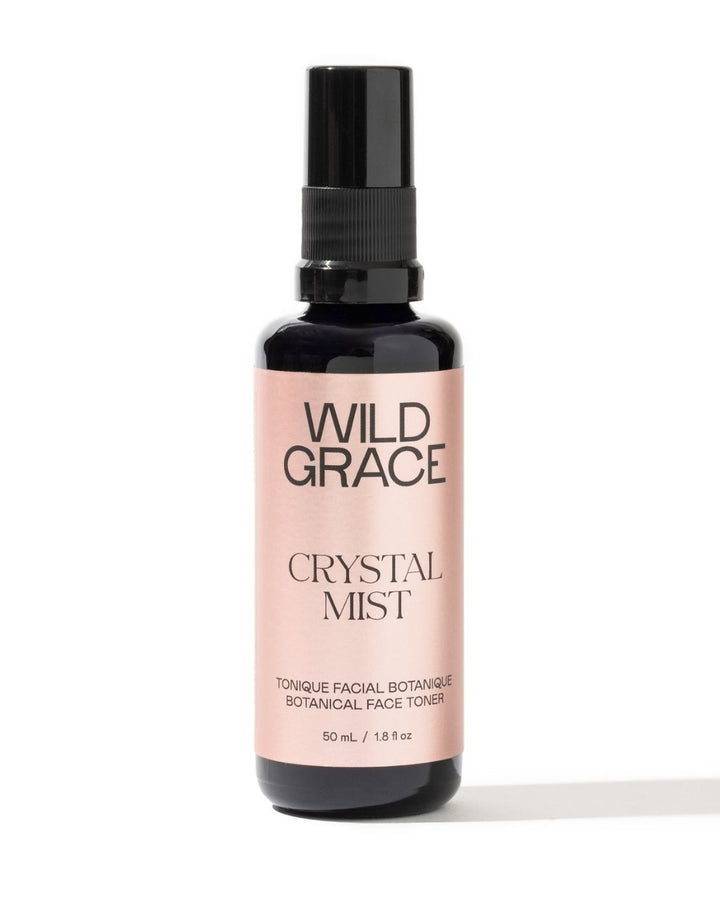 A bottle of Wild Grace Crystal Mist facial toner with a black spray top and a pale pink label, set against a plain white background.