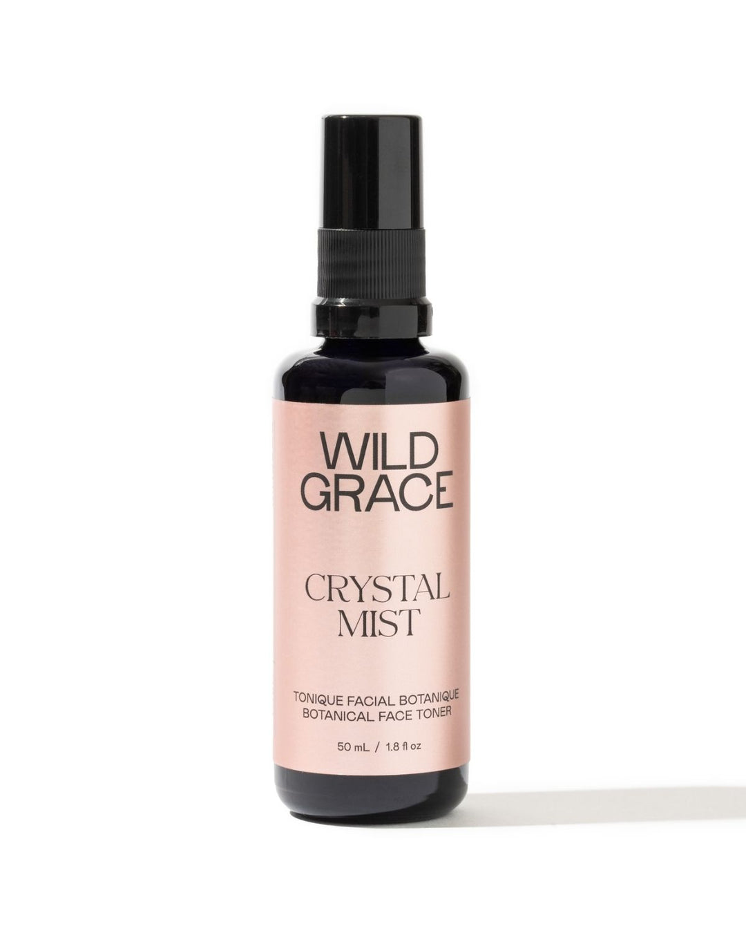A bottle of Wild Grace Crystal Mist facial toner with a black spray top and a pale pink label, set against a plain white background.