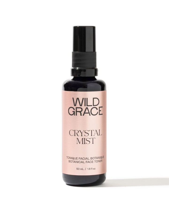 A bottle of Wild Grace Crystal Mist facial toner with a black spray top and a pale pink label, set against a plain white background.