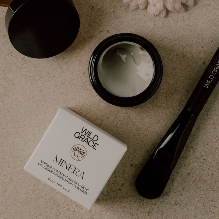 Wild Grace Minera facial mask packaging with a black mask container and applicator on a textured surface.