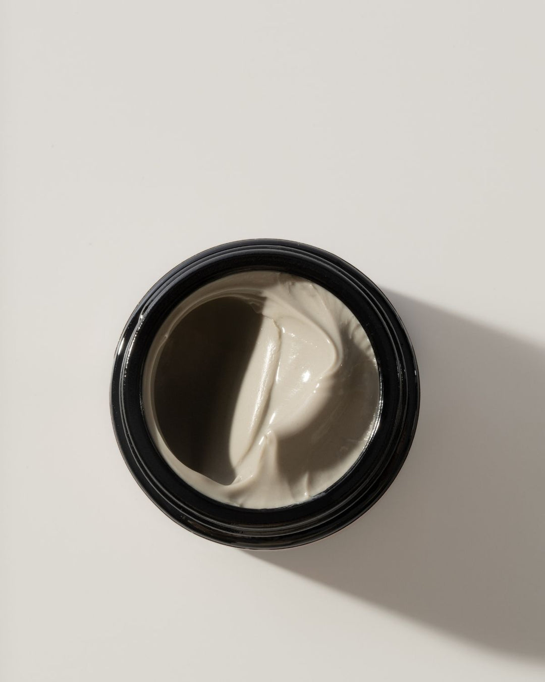 Jar of gray cream on a light beige background