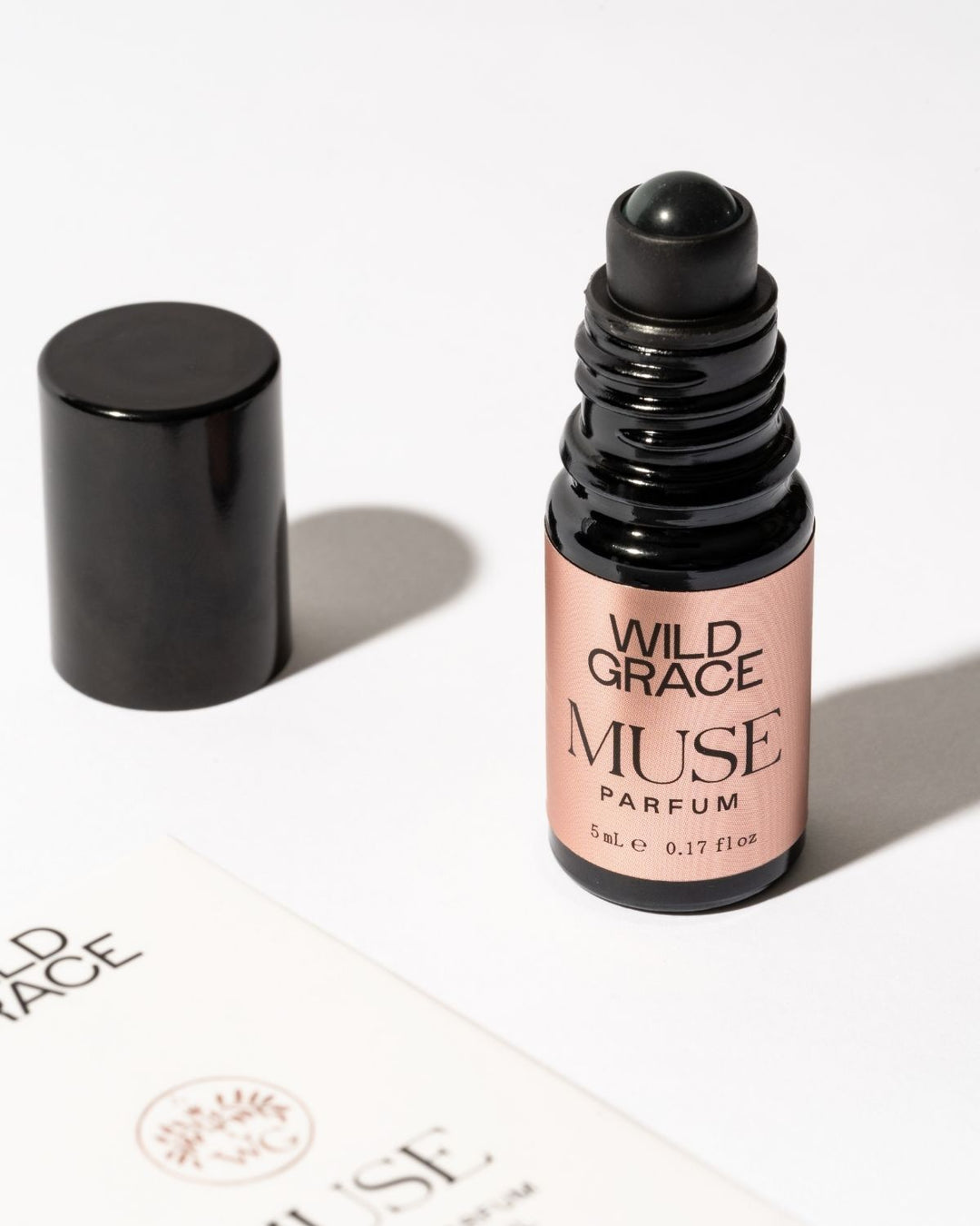 Black MUSE perfume oil bottle by wild grace with pink label on a white background