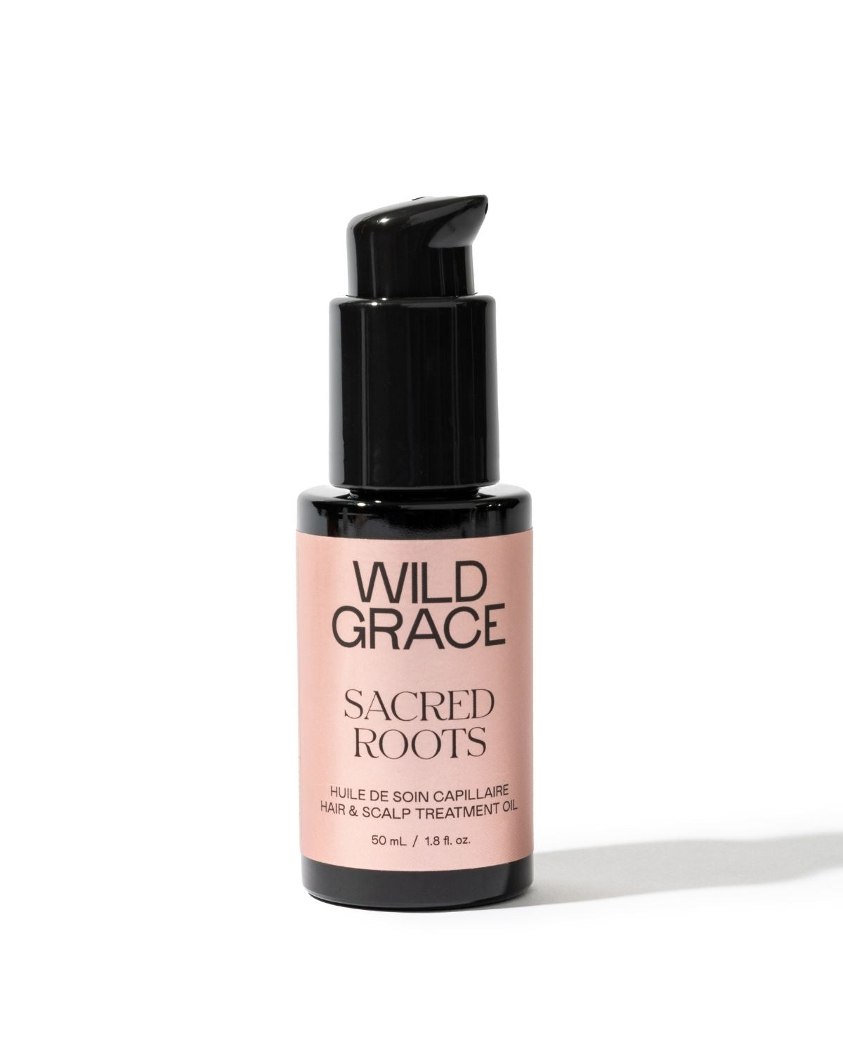 Wild Grace Sacred Roots Hair & Scalp Treatment Oil in a 50 mL pump bottle, featuring a black bottle and cap with a light pink label on a white background.
