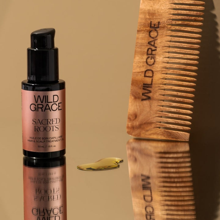 Wild Grace hair oil bottle and wooden comb on a beige background