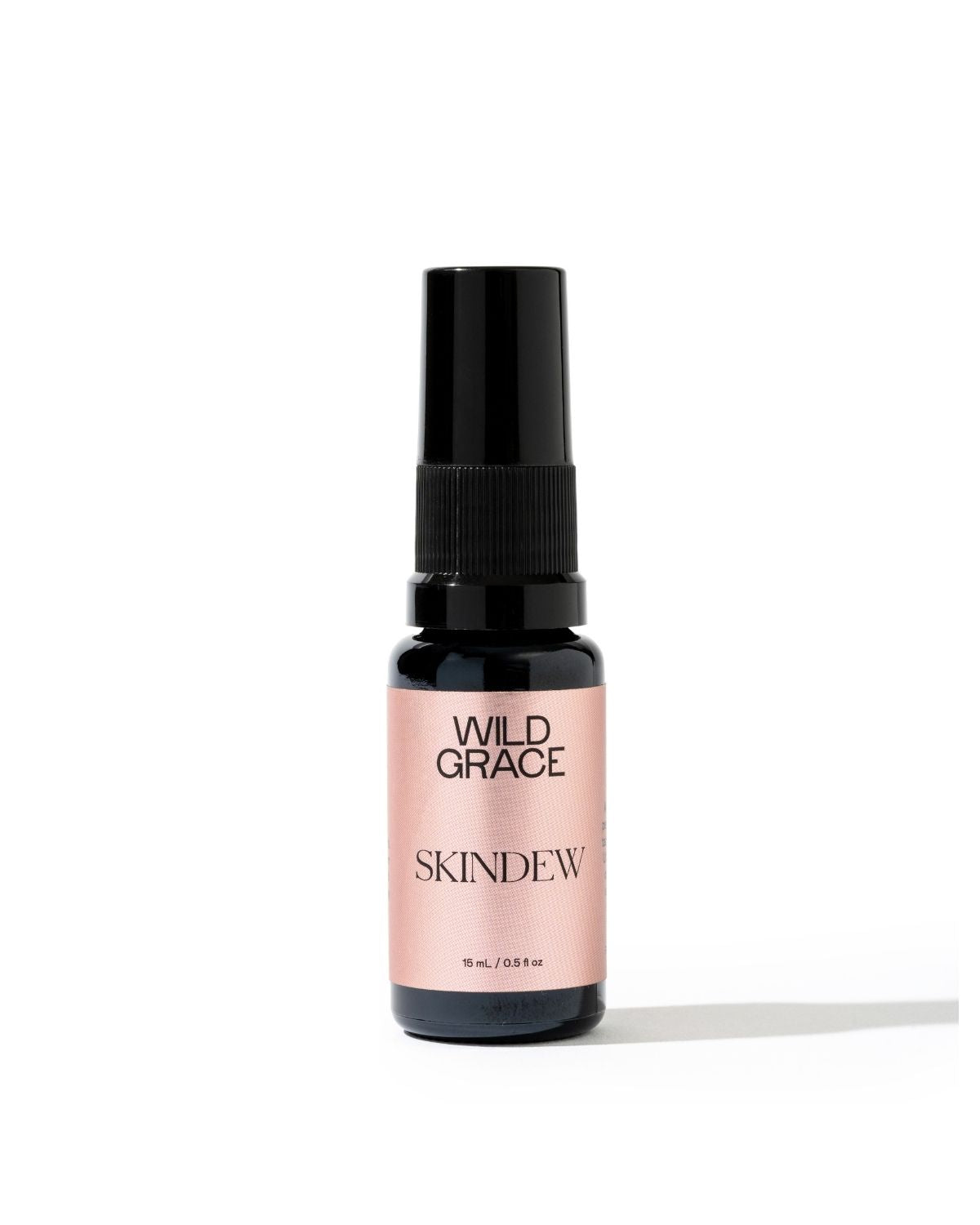 A small bottle of Wild Grace Skindew spray with a black pump and a pale pink label, set against a plain white background.
