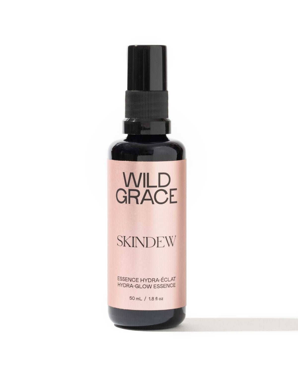 A 50 mL bottle of Wild Grace Skindew Hydra-Glow Essence, featuring a black spray nozzle and a pale pink label on a white background.