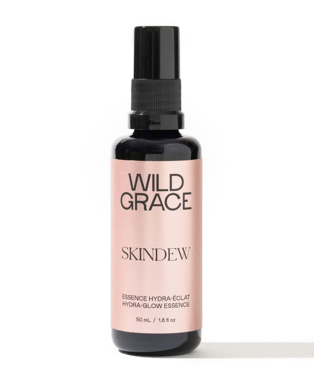 A 50 mL bottle of Wild Grace Skindew Hydra-Glow Essence, featuring a black spray nozzle and a pale pink label on a white background.