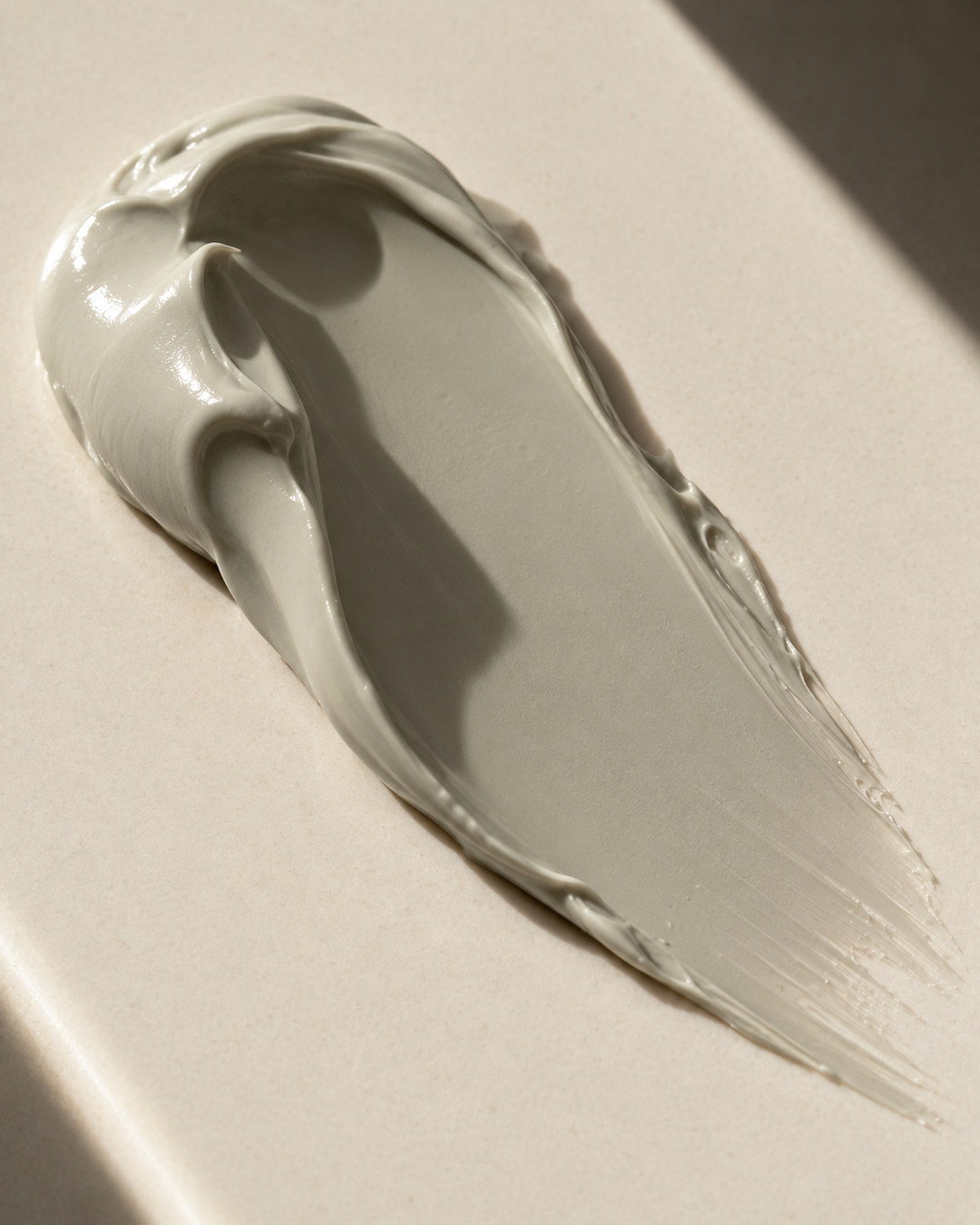 swab showing the creamy texture of face mask. the color of mask is grey.