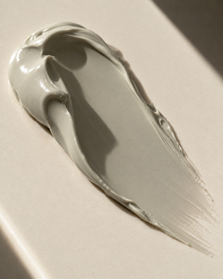 swab showing the creamy texture of face mask. the color of mask is grey.