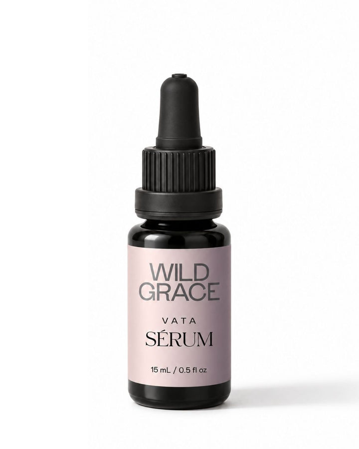 A small dropper bottle of Wild Grace Vata Sérum serum on a clean white background. The bottle is made of dark amber glass with a black dropper cap and features a light dusty lavender label with black text.
