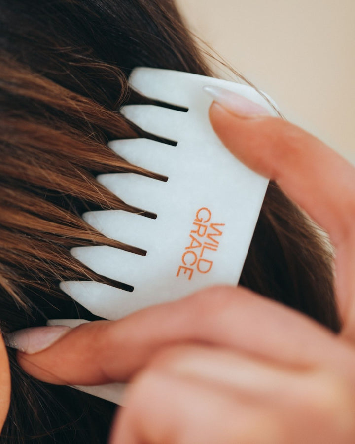 Woman using a white jade scalp comb with &