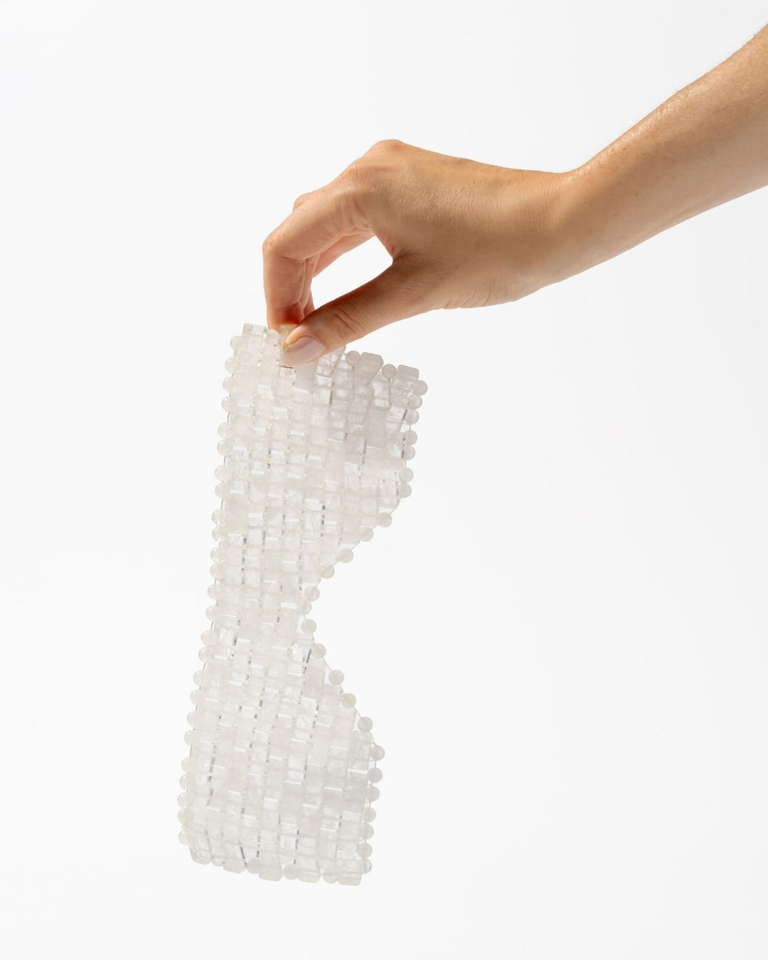 A hand holding a translucent white beaded mesh sleeve or glove against a plain white background.