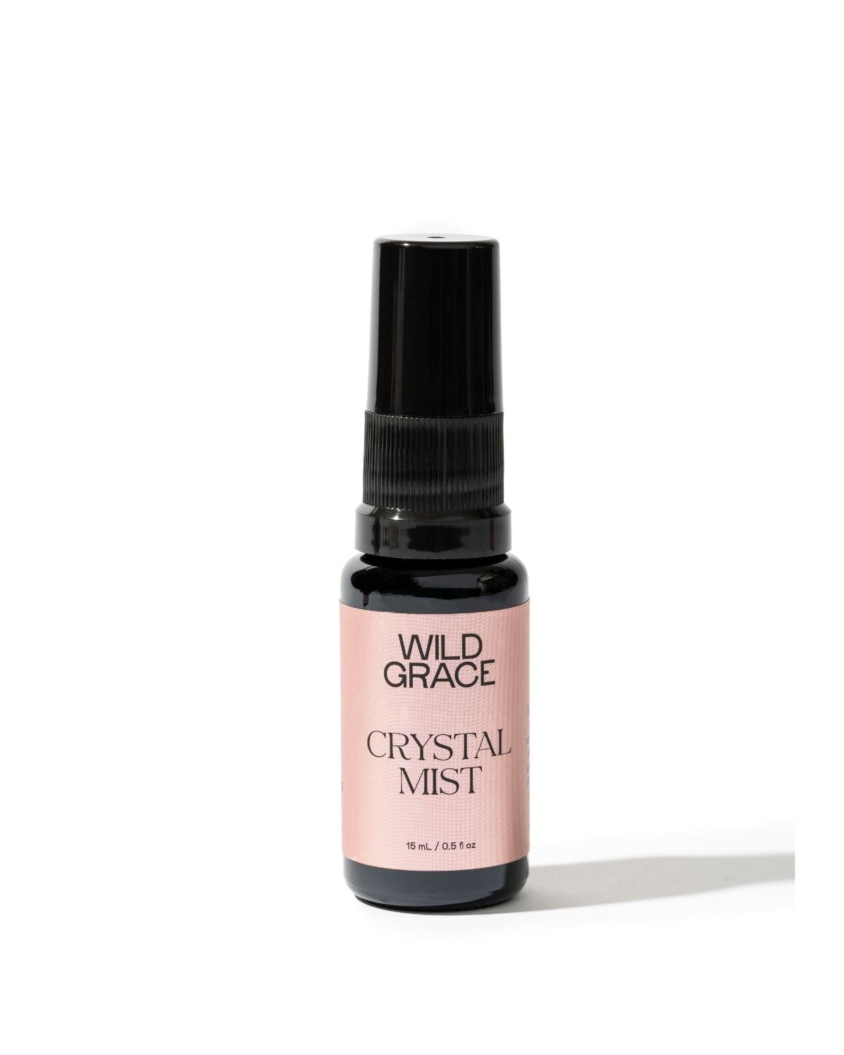 A small spray bottle of Wild Grace Crystal Mist with a black pump and a light pink label, set against a plain white background.