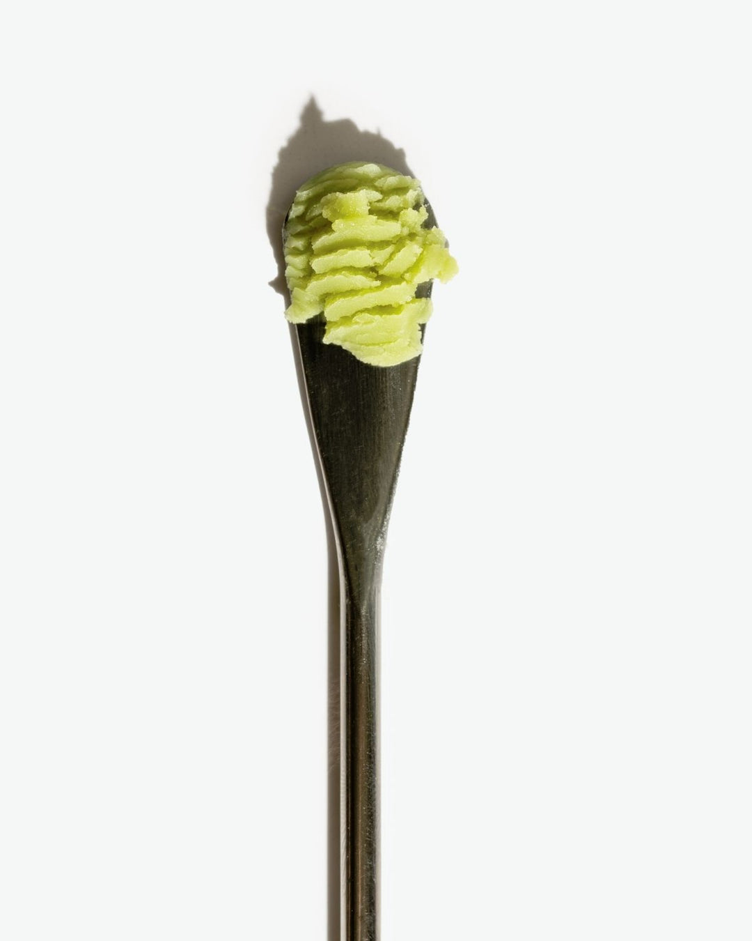Spoon with green substance on a white background