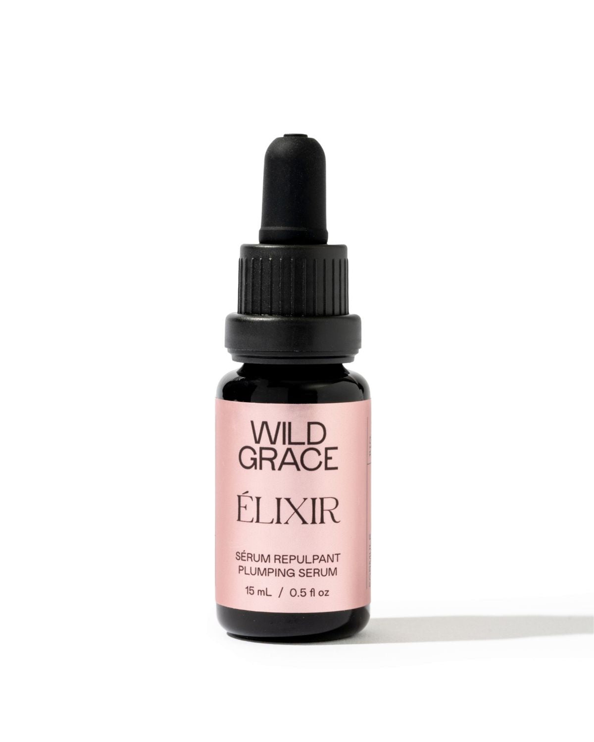 A small amber glass dropper bottle of Wild Grace Élixir plumping serum with a black dropper cap and a light pink label, centered on a white background.