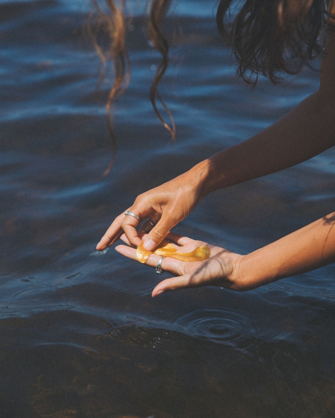 Person holding a golden eyes eye patches over water with ripples