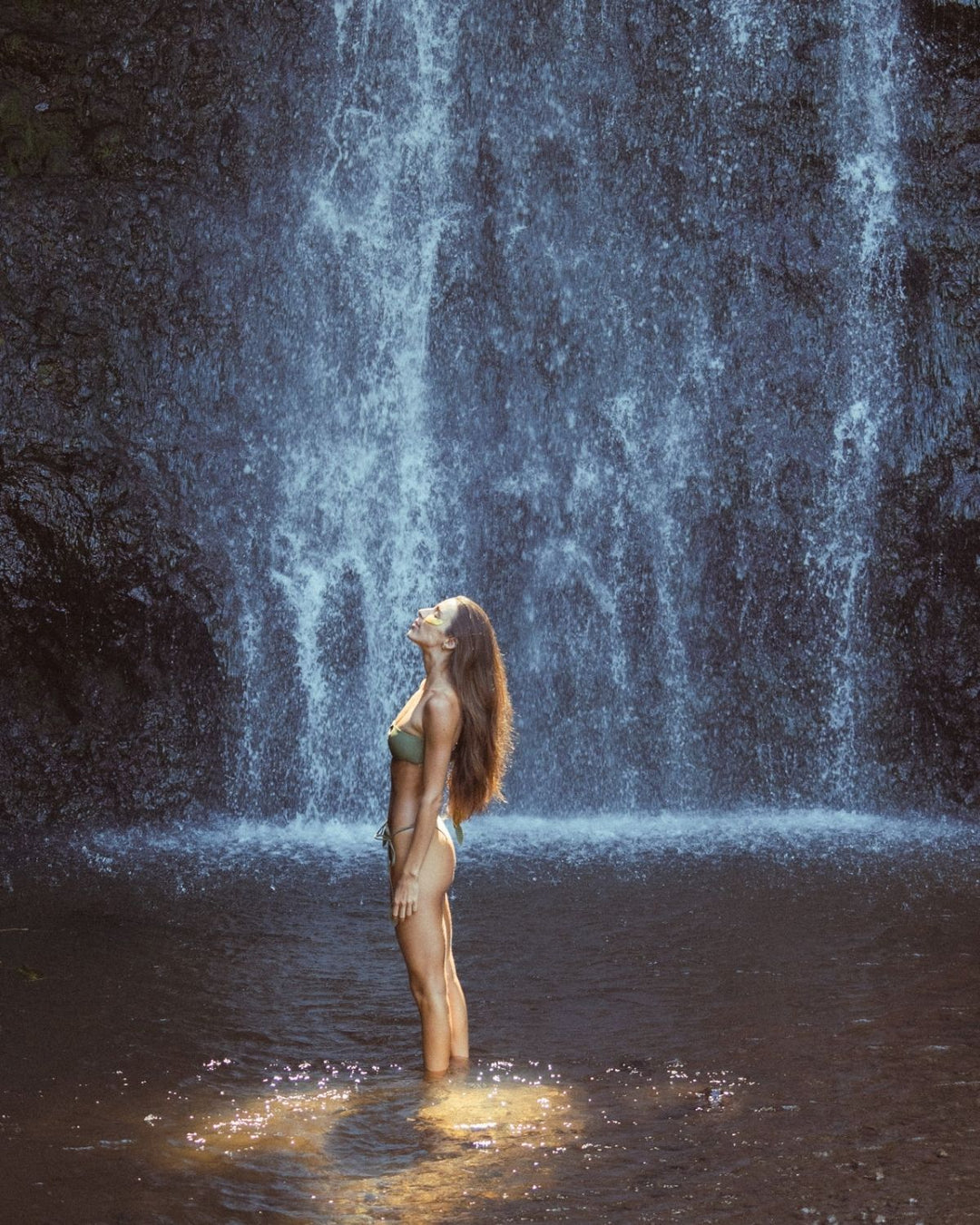 Woman standing in front of a waterfall with golden eyes eye masks