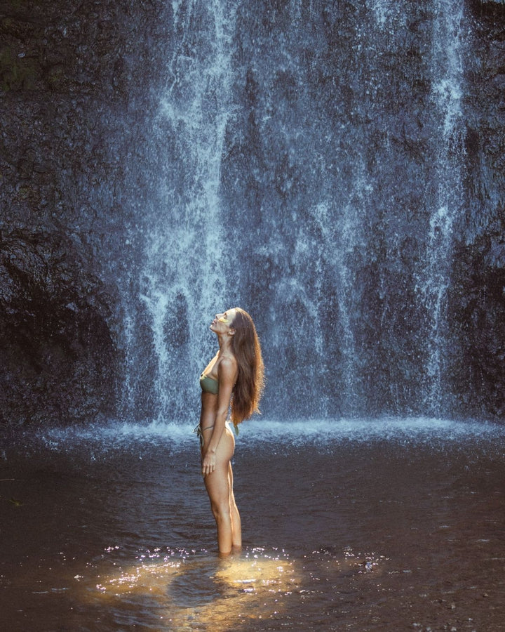 Woman standing in front of a waterfall with golden eyes eye masks