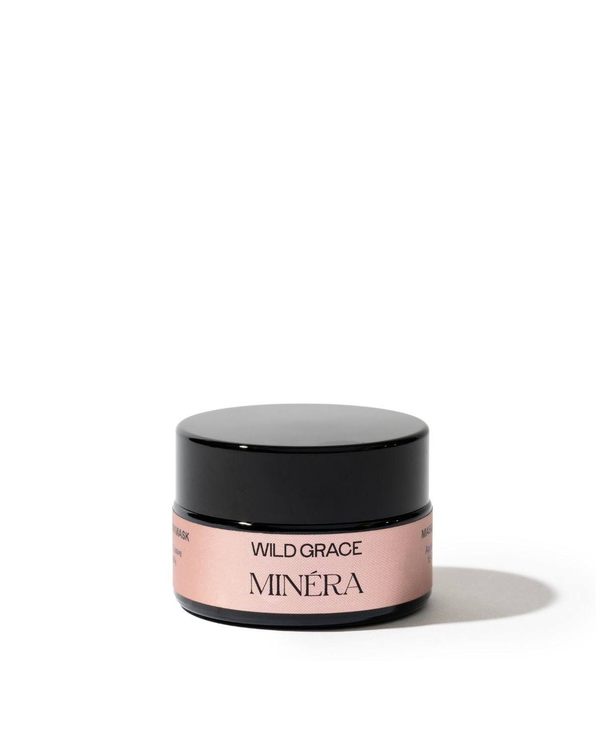 A small cosmetic jar with a glossy black lid and a pale pink label reading 'WILD GRACE MINÉRA' on a clean white background.