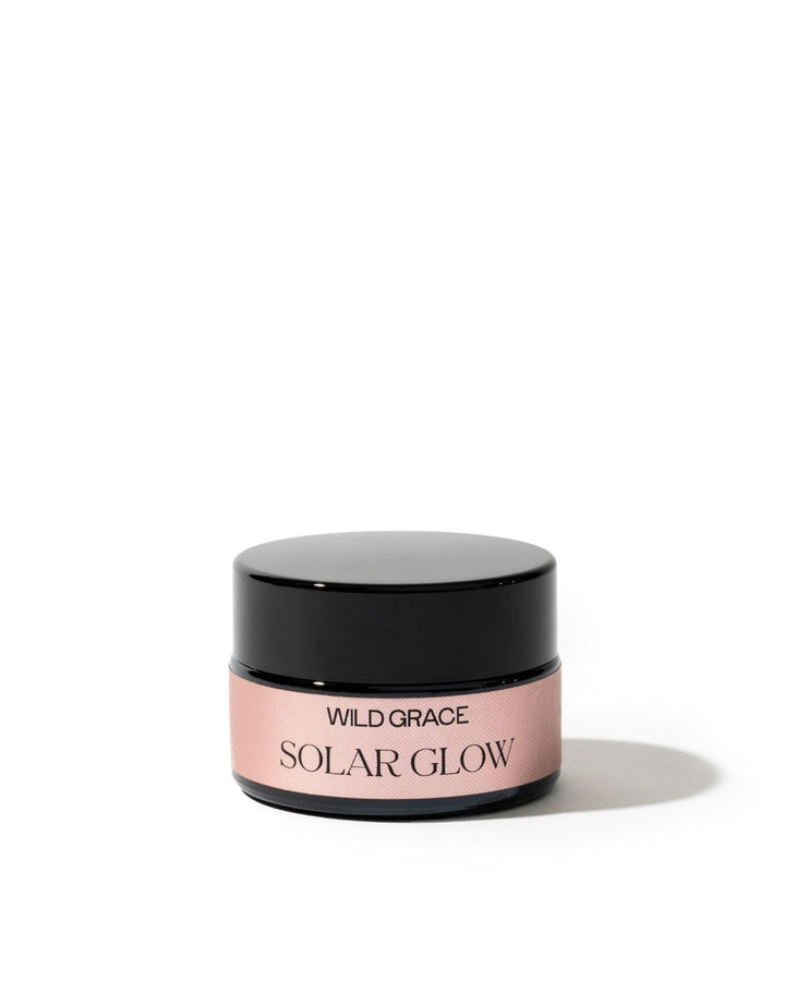 A small cosmetic jar with a glossy black lid and a dusty pink label reading &