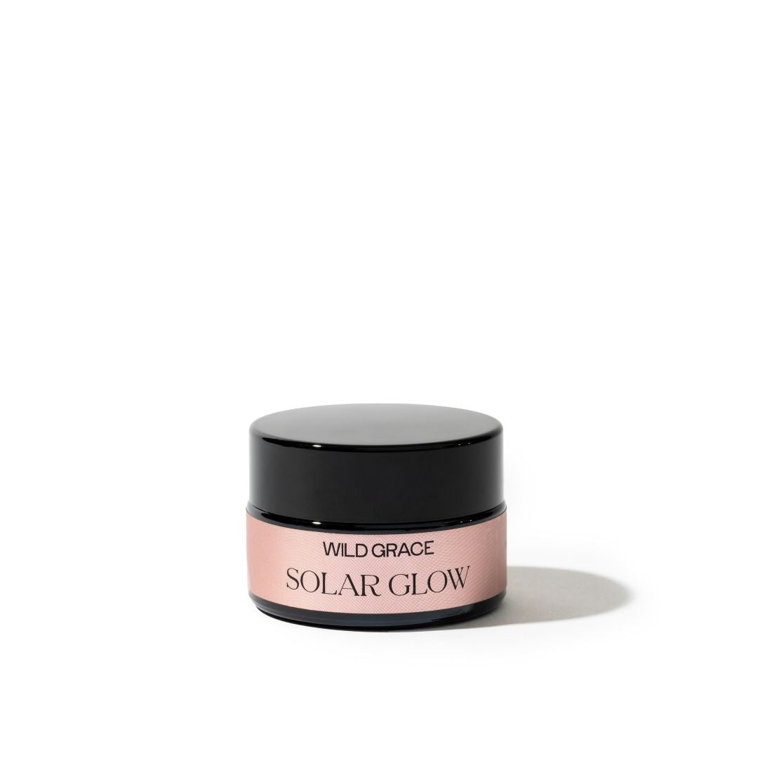 Cosmetic jar labeled 'Solar Glow' by 'Wild Grace' on a white background