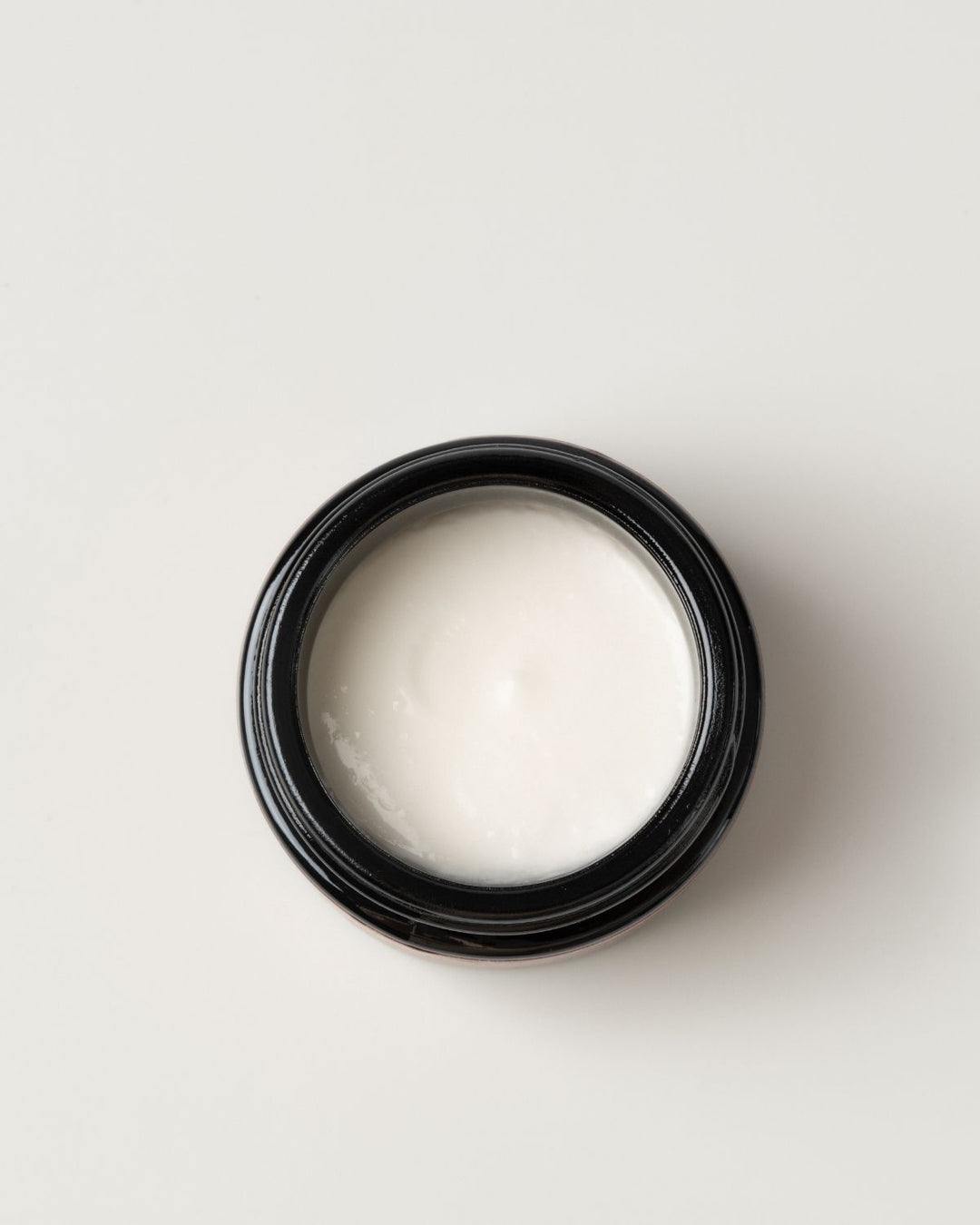 Black container with white moon dust wild grace exfoliant on light gray background