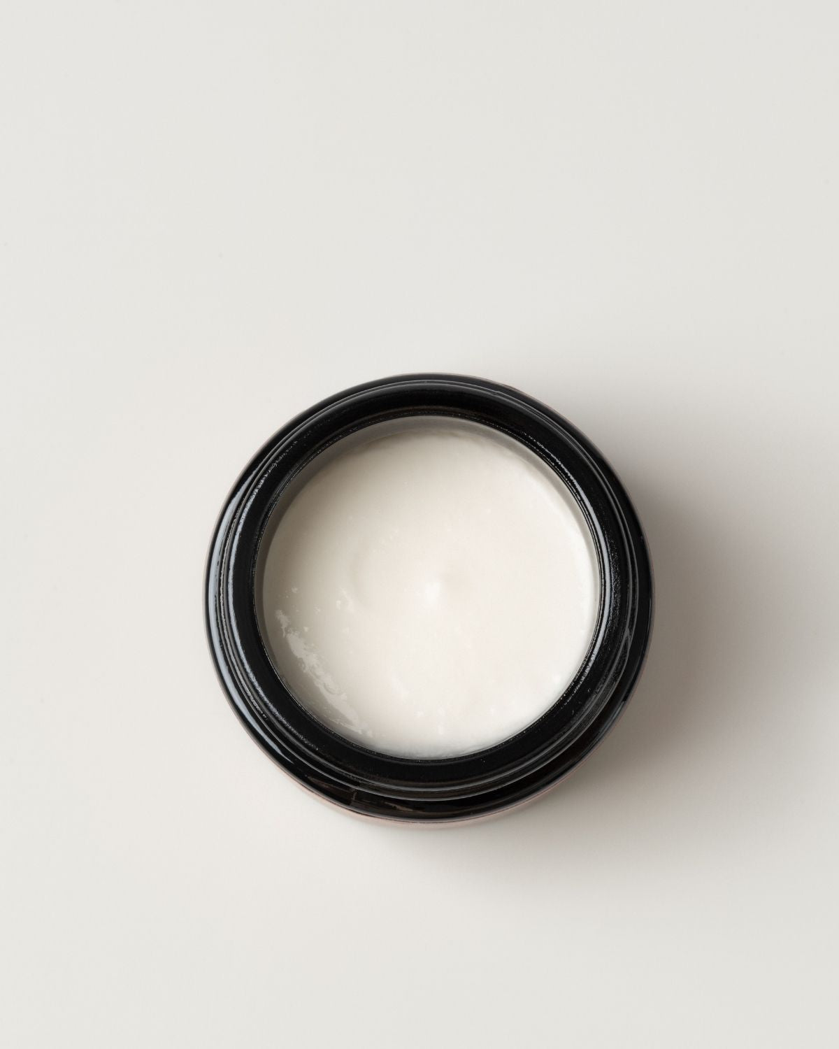 Black container with white moon dust wild grace exfoliant on light gray background