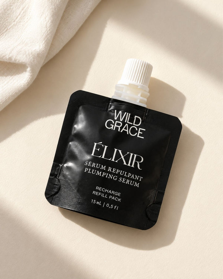  black refill pouch of Wild Grace Élixir plumping serum against a warm beige background with soft window shadows.