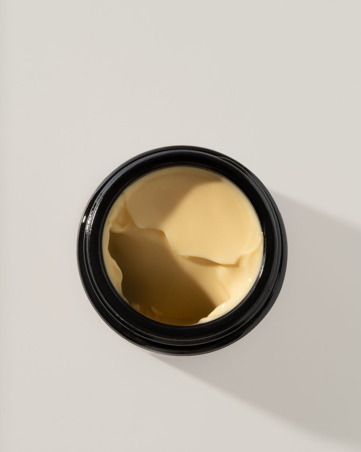 Black container with solar glow wild grace cream on a light gray background