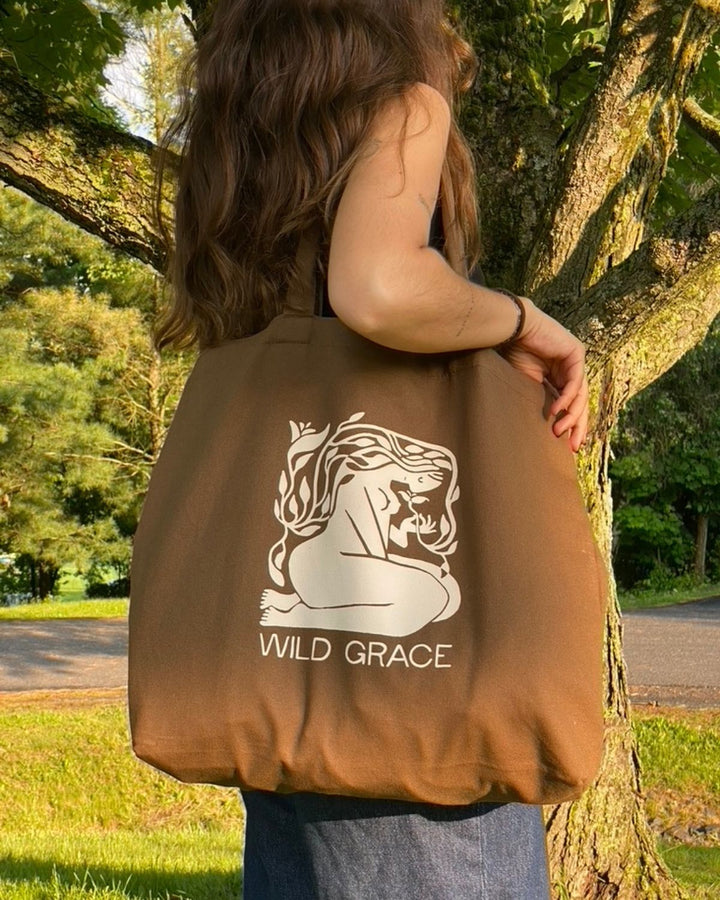 Person holding a brown tote bag with &